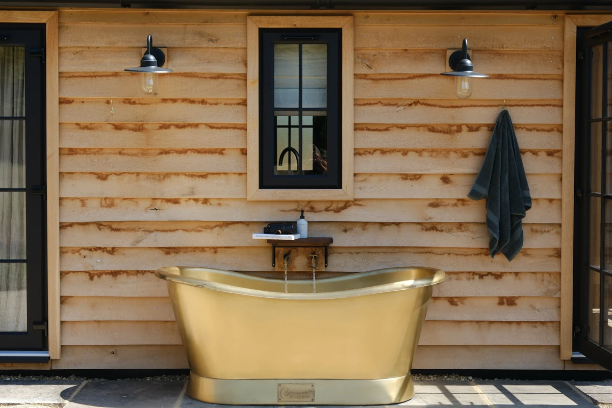 Ember brass bath against timber cladding